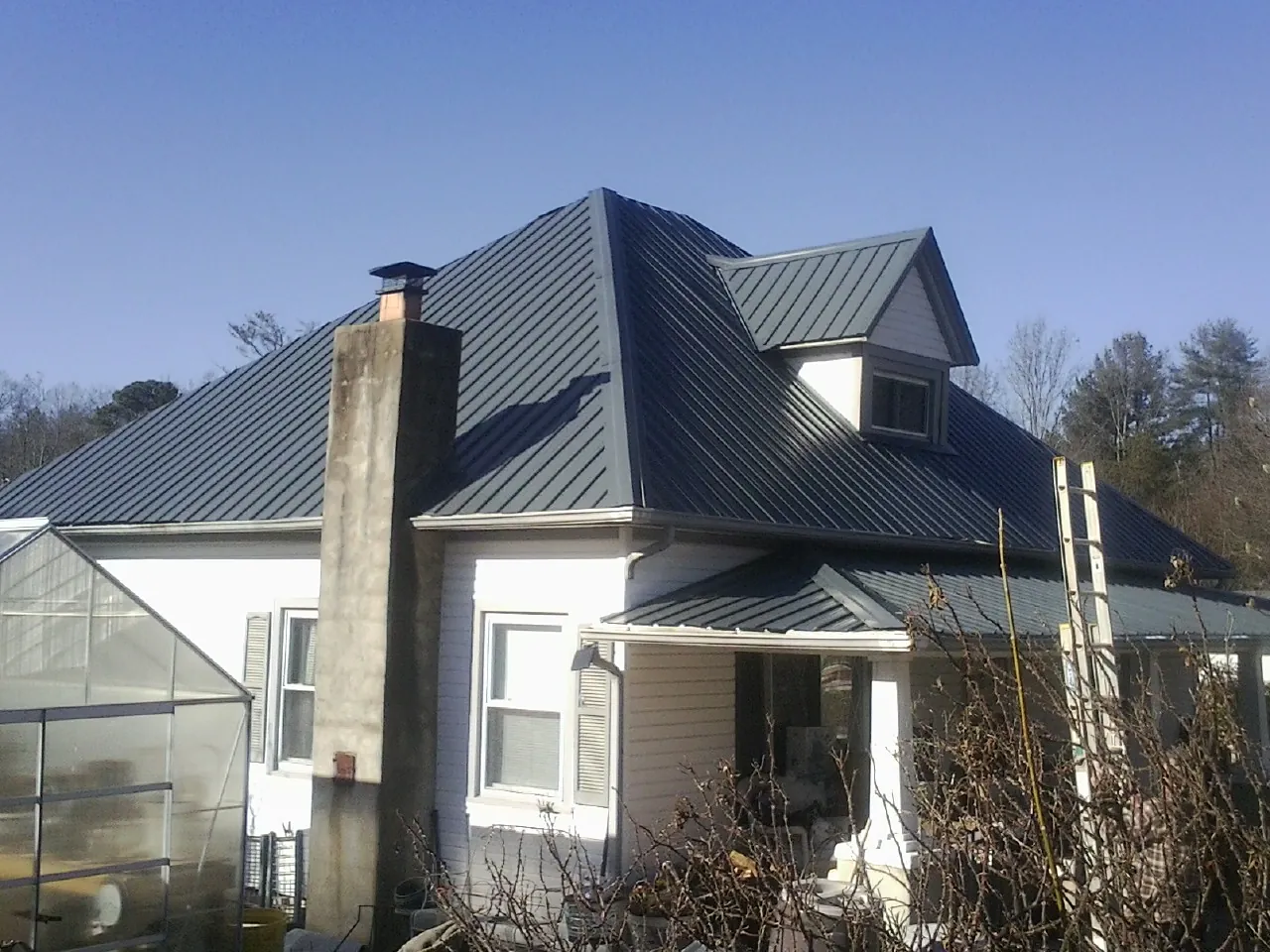 Dark blue standing seam metal roof on a white farmhouse with dormer — Slate & Tile Roof Repair by Roofing Brothers in Frazier Park