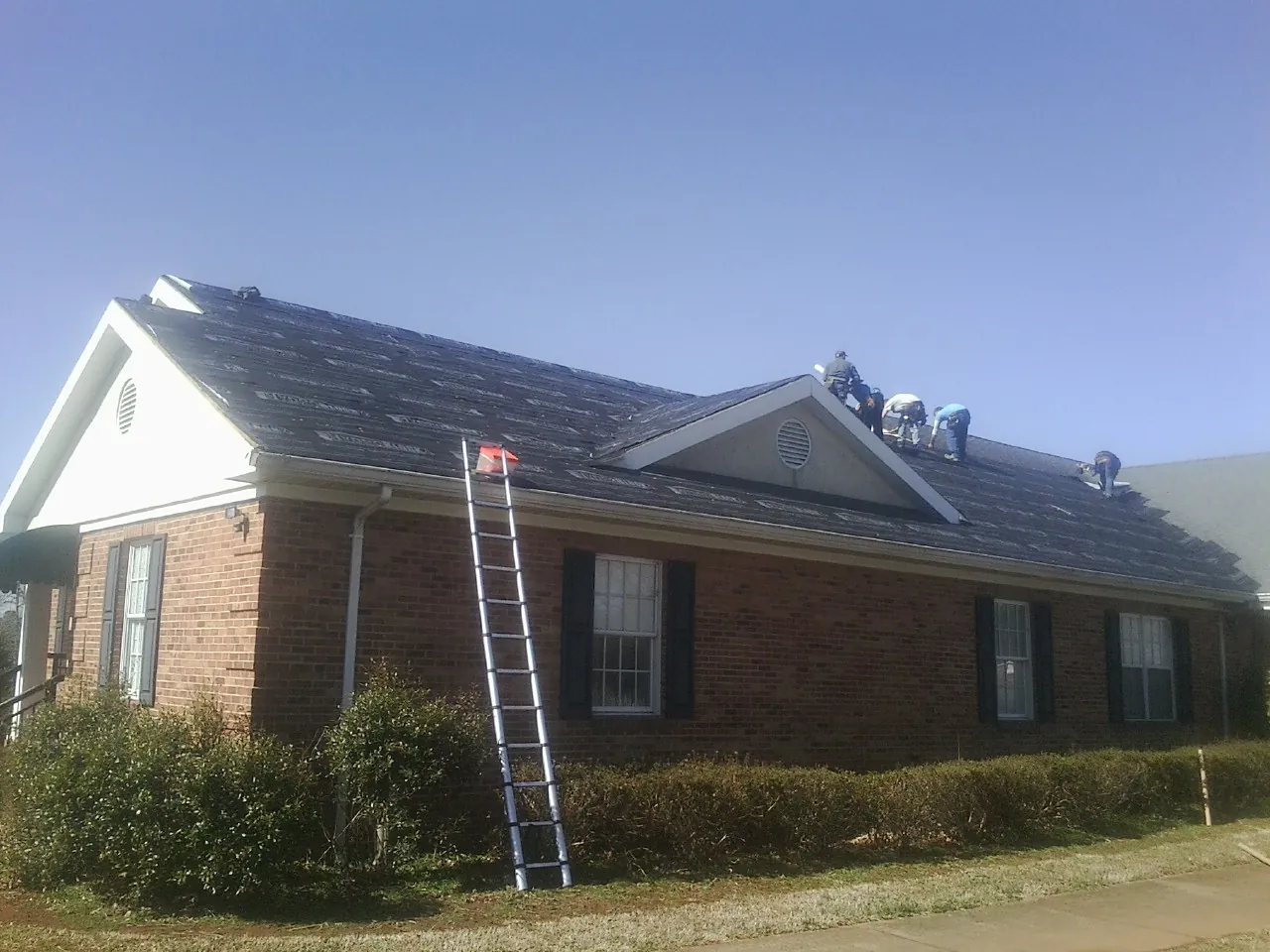 Crew tearing shingles off a brick ranch roof with a ladder set — Metal Roof Repair work by our crew in Frazier Park