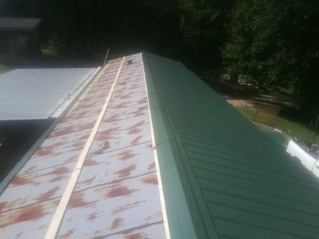 Old rusted panels beside newly installed green metal roofing — Wind Damage Roof Repair by Roofing Brothers in Frazier Park