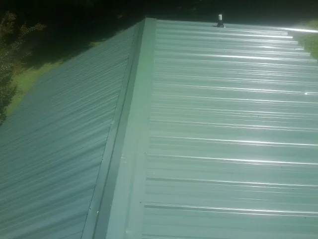 New green metal panels meeting at the ridge of a roof — Flat Roof Repair work by our crew in Frazier Park