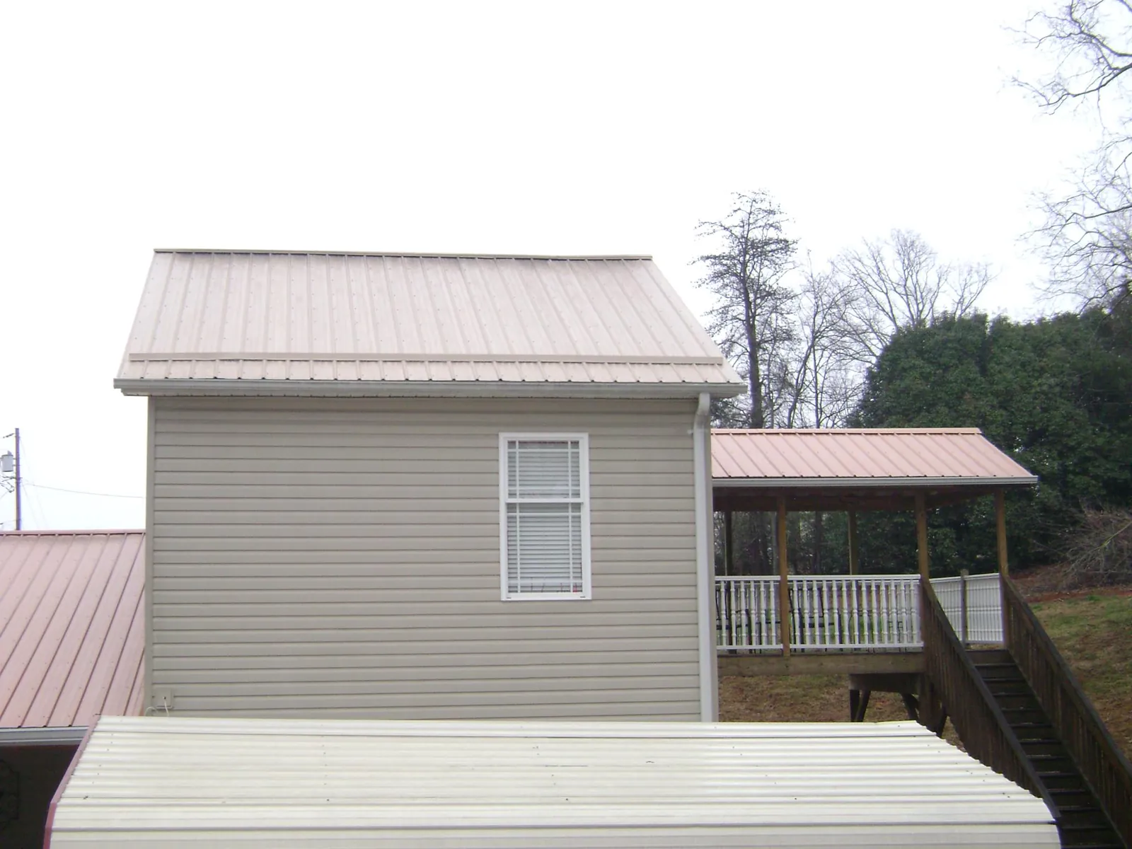Tan metal roofs on a two story addition and attached porch, from a Roof Replacement job in Frazier Park