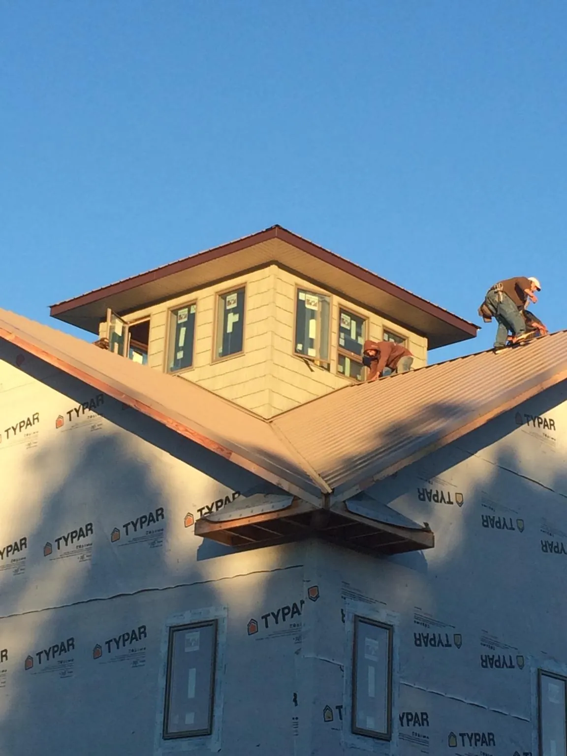 Roofers working around a rooftop cupola on a new metal roof at sunset — Roof Waterproofing in Frazier Park by Roofing Brothers